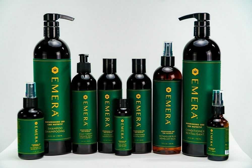 Emera haircare product line, including shampoo, conditioner, and various serums in green bottles.