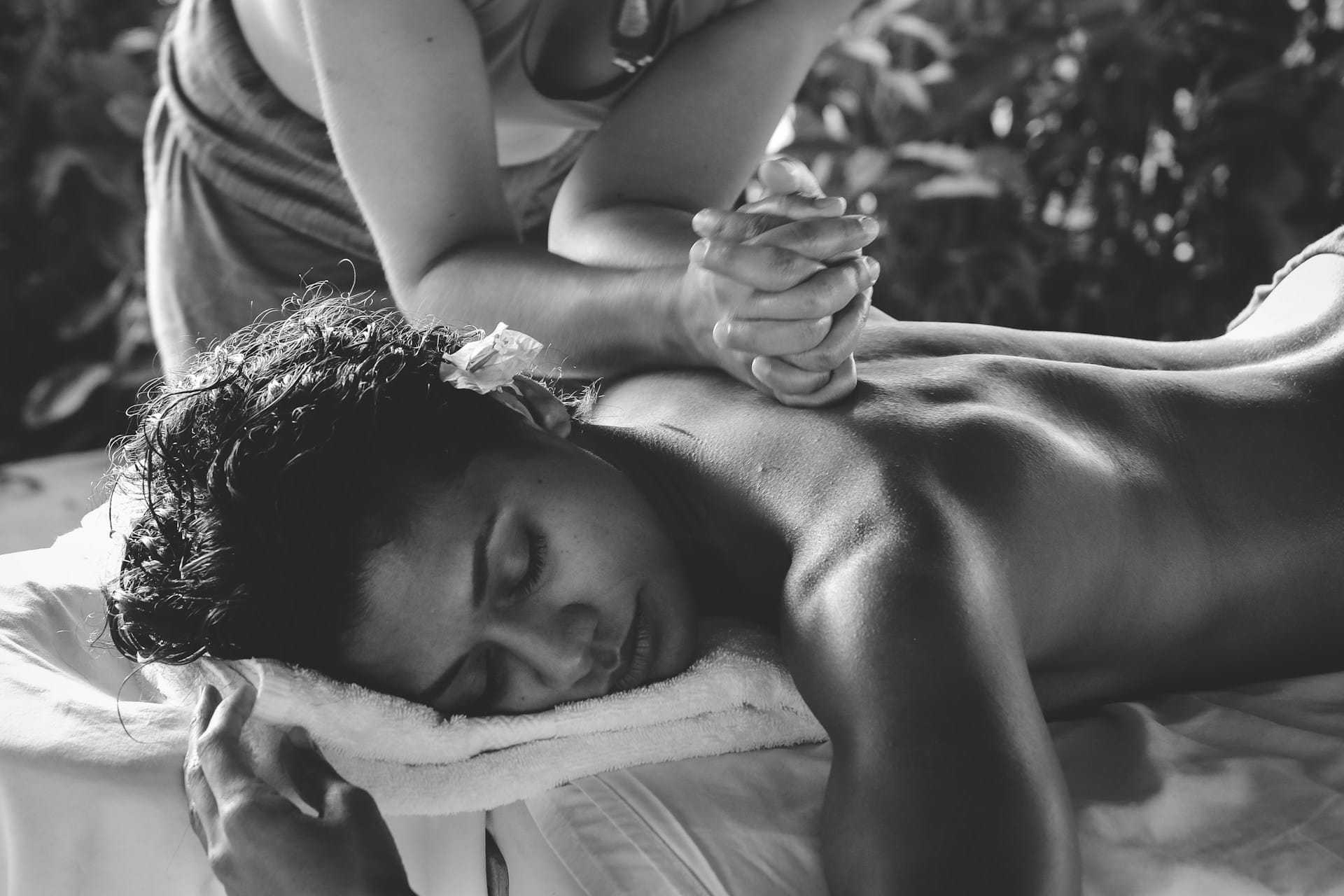 Receiving a relaxing back massage outdoors, surrounded by greenery.