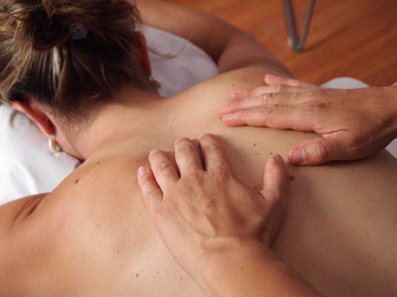 Person receiving a back massage on a white surface in a calming environment.
