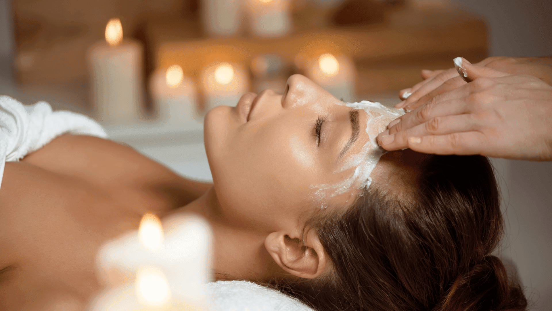Facial treatment in serene spa setting with candles creating a relaxing atmosphere.