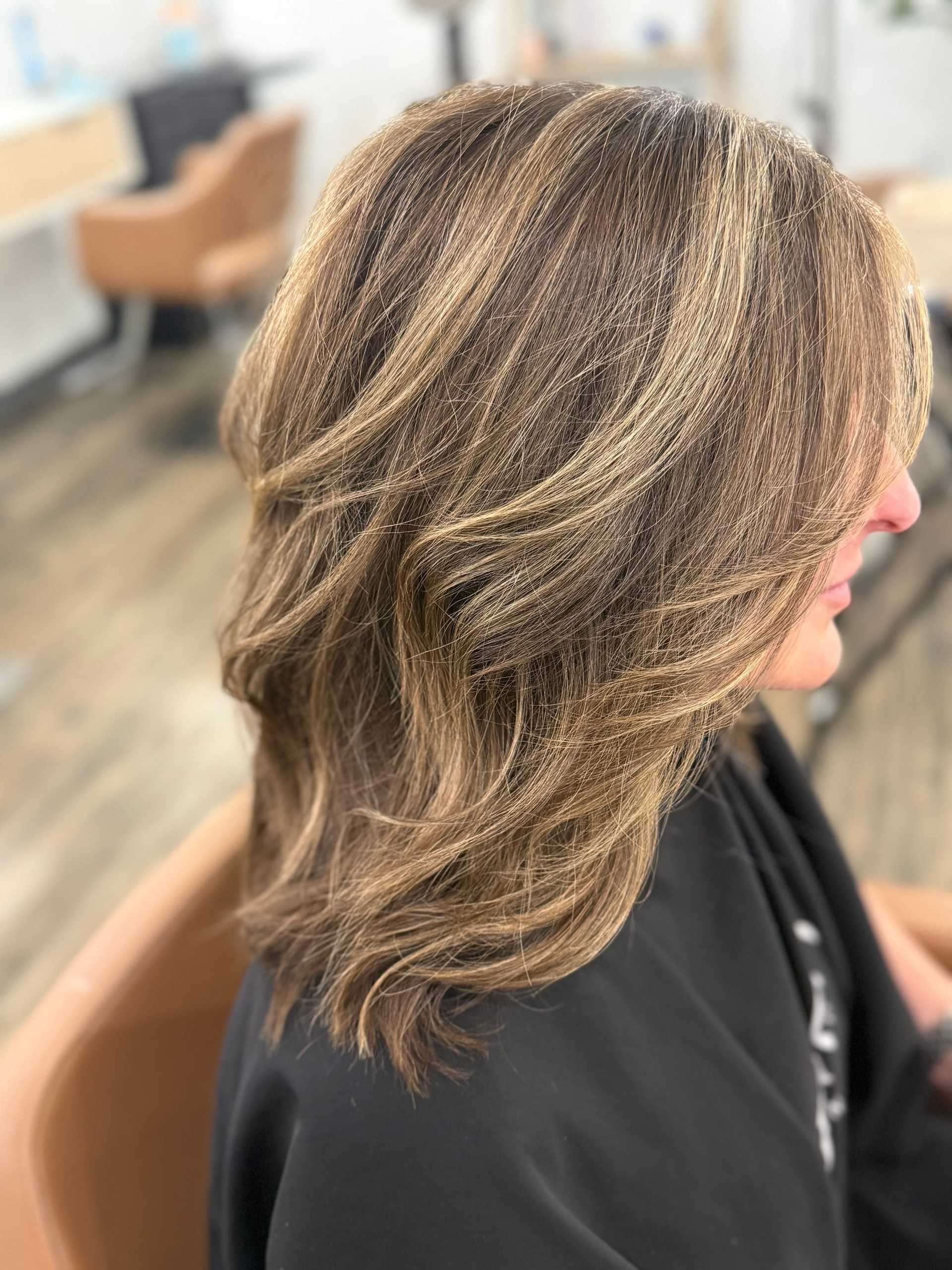 Brunette hair with blonde highlights styled in soft waves in a salon setting.